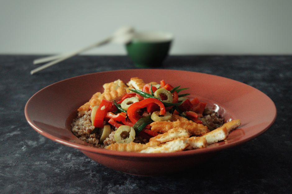 A healthy quinoa bowl topped with vibrant vegetables and served in a stylish terracotta dish.