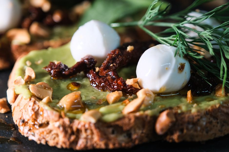 Delicious slice of bread topped with avocado, mozzarella, nuts, and sundried tomatoes.